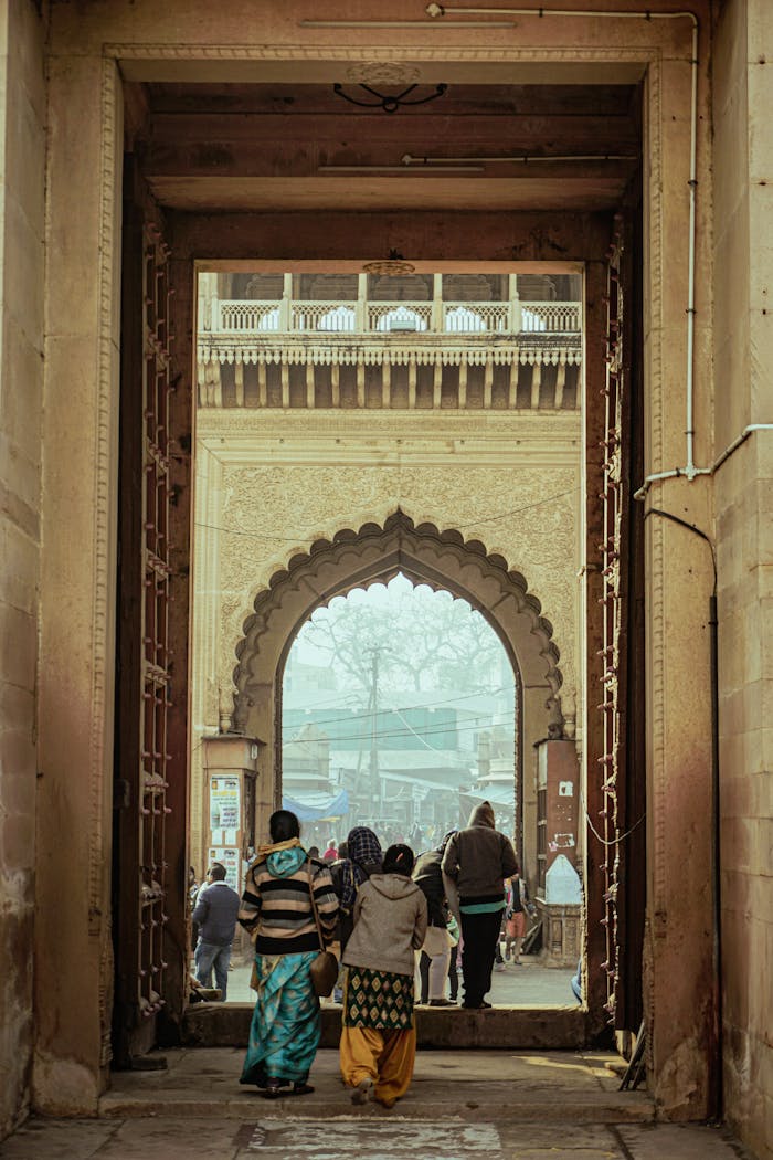 People walking through a historic archway gate in Vrindavan, India. Captures vibrant cultural architecture.