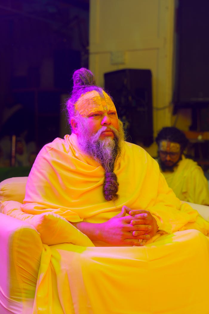 A spiritual leader adorned in orange robes participates in a religious ceremony in Vrindavan, India.